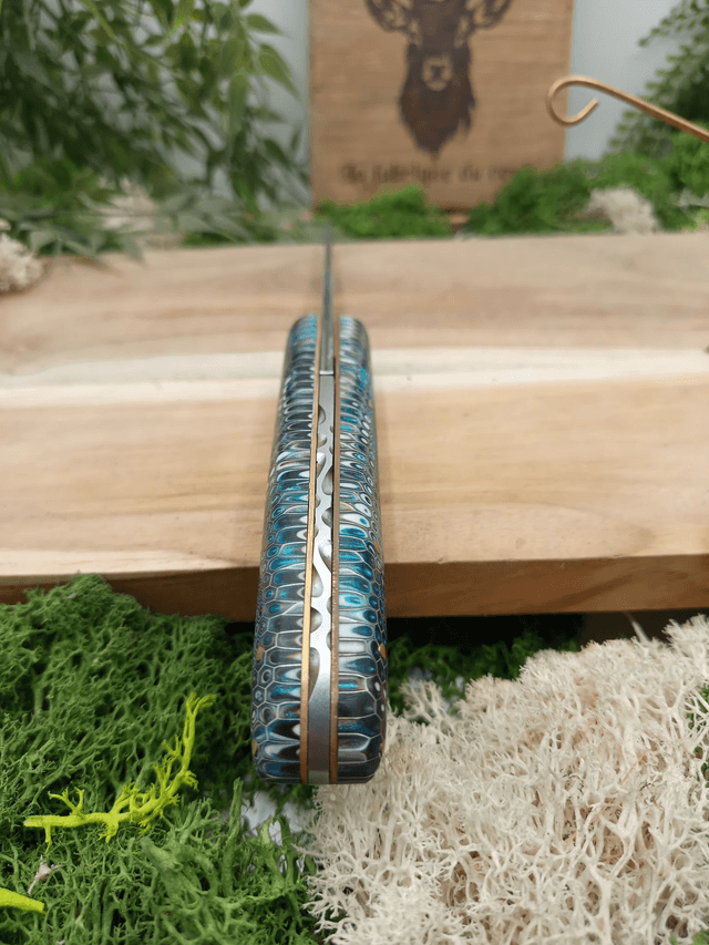 Couteau pliant artisanal “Le Cerf” – Édition Prestige n°003 – lame damas VG10 – manche résine époxy nid d’abeille – platines laiton et cuivre